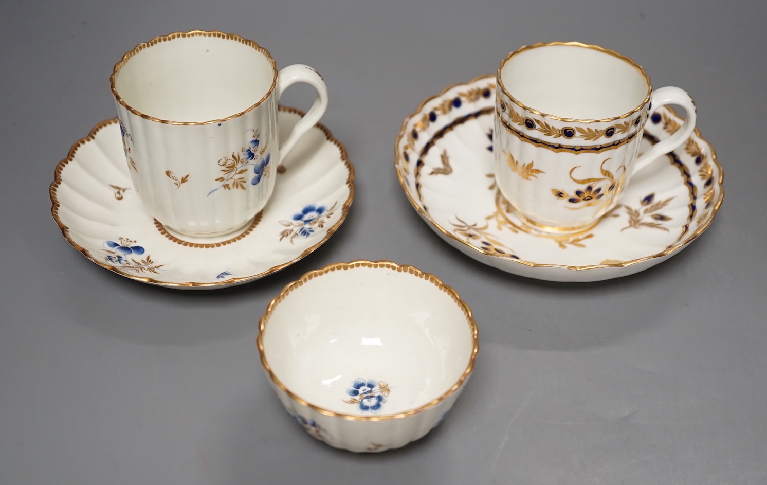 A Worcester fluted coffee cup, teacup and saucer painted with dry blue flowers and gilt foliage and a fluted coffee cup and saucer with blue and gilt decoration c.1775 and later